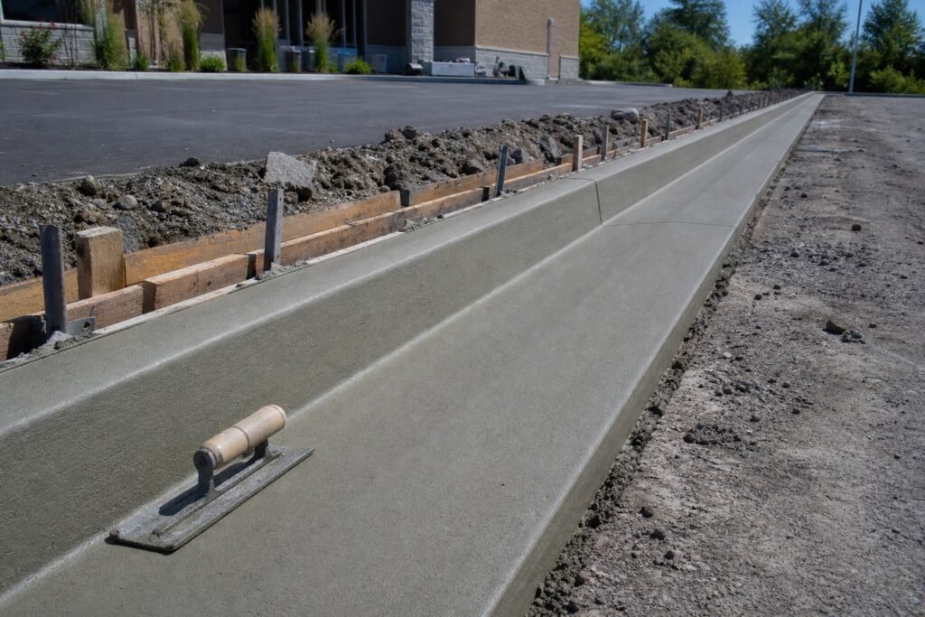 Freshly poured concrete curb and gutter running along a commercial lot